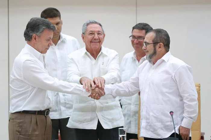 Presiden Kuba Raul Castro, (tengah) berdiri dengan Presiden Kolombia Juan Manuel Santos, (kiri), dan pemimpin pemberontak FARC Rodrigo Londono berjabat tangan di Havana./Business Insider/Reuters