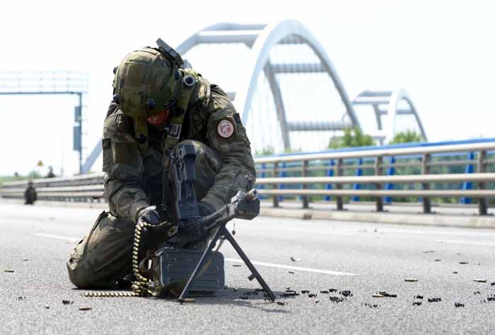  A Polish soldier reloads his weapon while securing a bridge. 