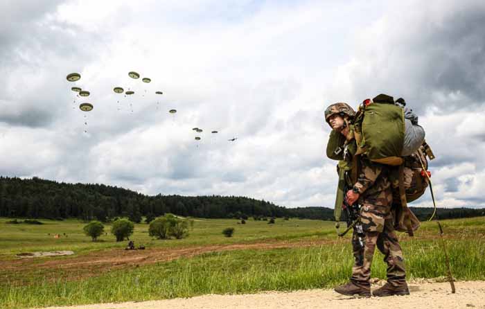 A French soldier watches soldiers descend from a Lockheed C-130 Hercules.